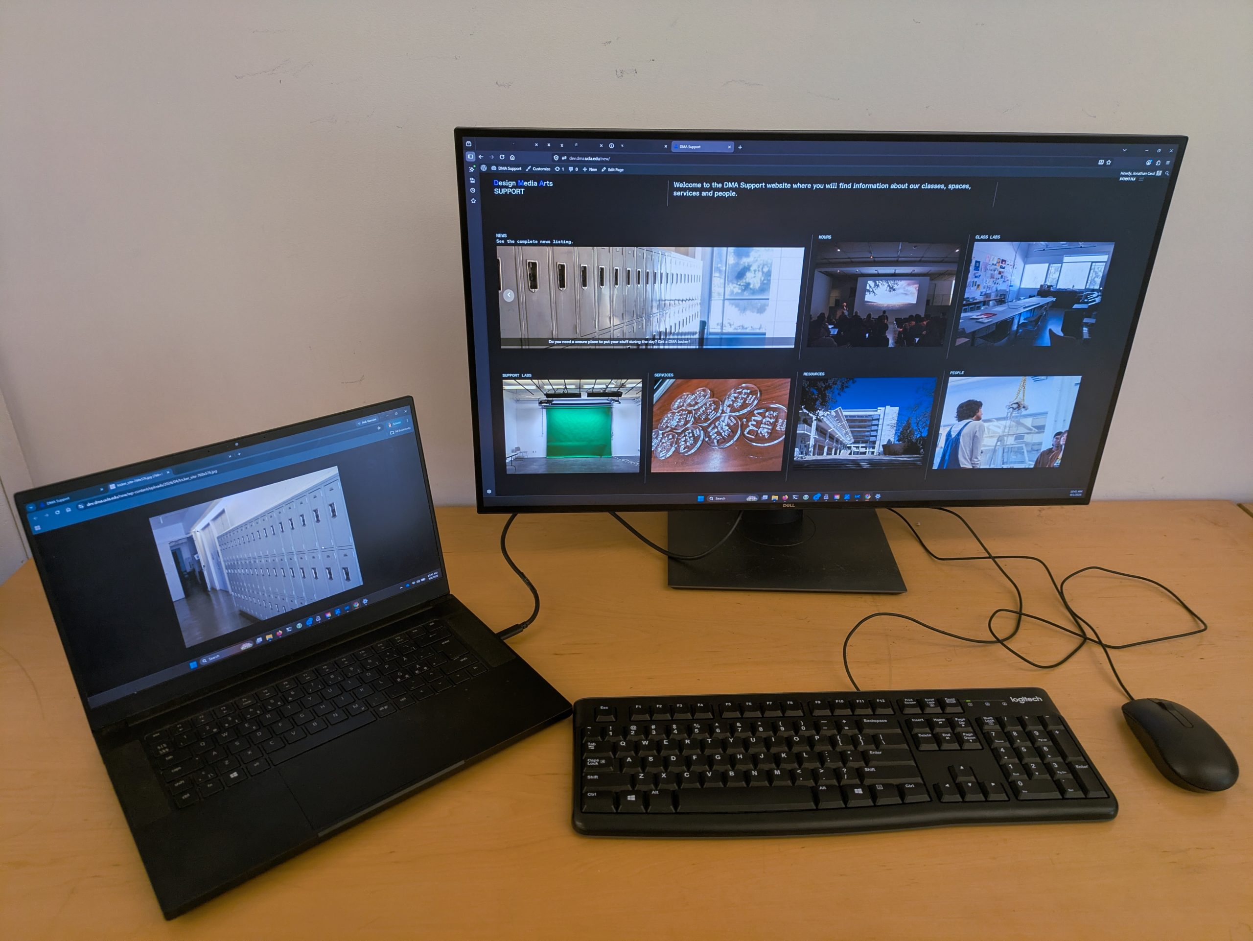 Photo of the top of a desk with keyboard, monitor, mouse and external monitor. A laptop is plugged in with charging cable from the monitor.