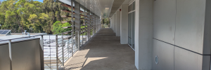photograph with single point perspective of a an exterior building balcony with trees in the background.