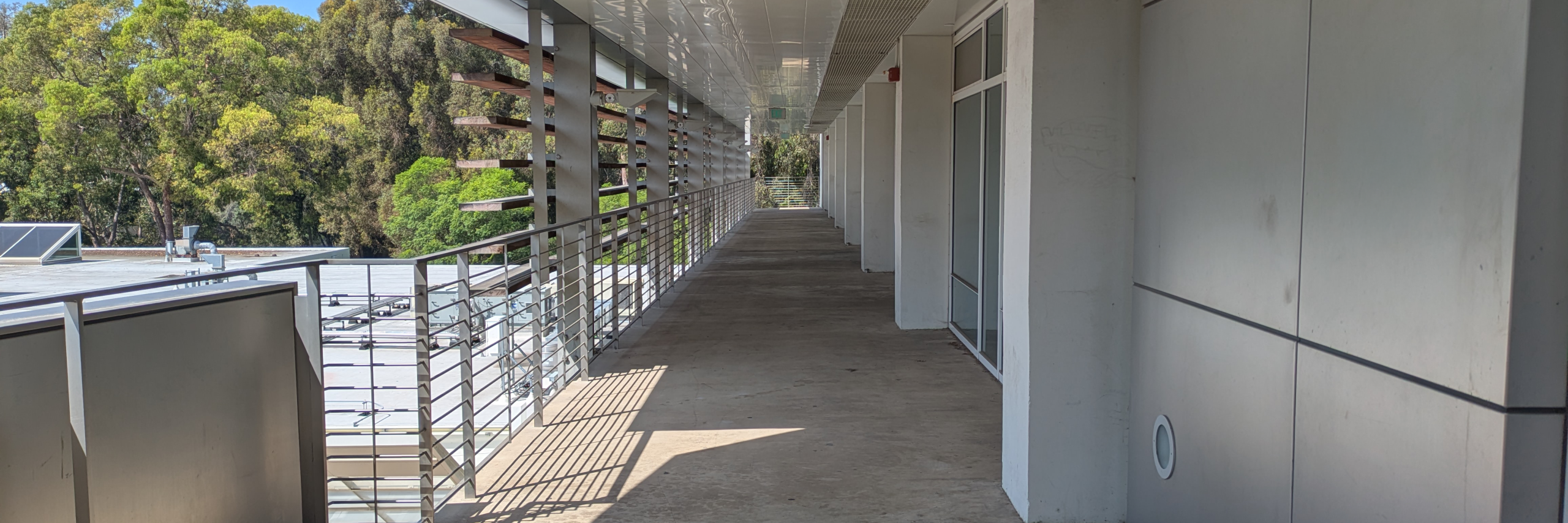 photograph with single point perspective of a an exterior building balcony with trees in the background.